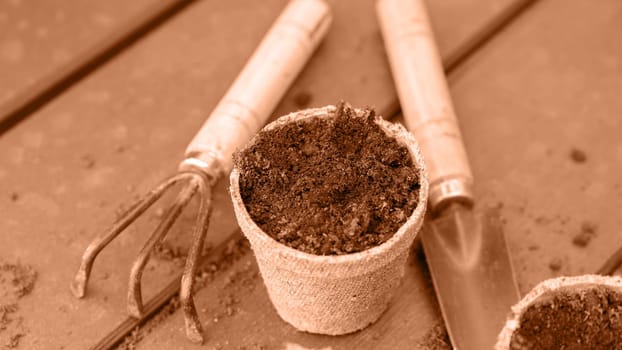 Eco friendly biodegradable peat pots and garden tools. Image toned in Peach Fuzz color of the year 2024. Spring natural gardening, eco, plant care, organic product.