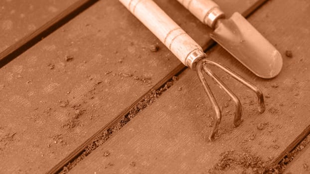 Old used garden tools shovel and rake. Image toned in Peach Fuzz color of the year 2024. Spring natural gardening, eco, plant care, organic product.