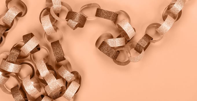 Strips of gold silver red sparkling chain garland. Image toned in Peach Fuzz color of the year 2024. Festive Christmas birthday decoration garland. Space for text