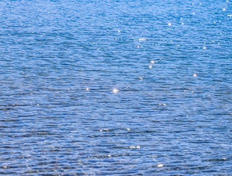 Blue sea in sunshine glow as surface background. Summer holidays and coastal nature concept