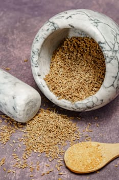 Whole dried anise seeds (Pimpinella anisum) in a ceramic mortar and pestle, with ground anise and star anise