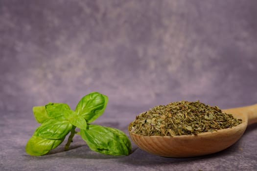 dried basil ground in a wooden spoon with freshly cut basil leaves