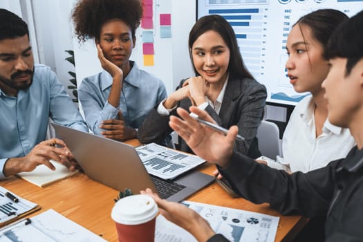 Multiracial analyst team use BI dashboard data to analyze financial report on meeting table. Group of diverse business people utilize data analysis by FIntech for success business marketing. Concord