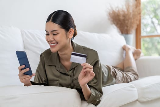 Young happy Asian woman buy product by online shopping at home while ordering items from the internet with credit card online payment protected by uttermost cyber security from online store platform