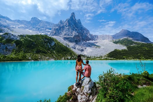 A couple of men and women visit Lago di Sorapis in the Italian Dolomites, milky blue lake Lago di Sorapis or Lake Sorapis Dolomites, Italy.