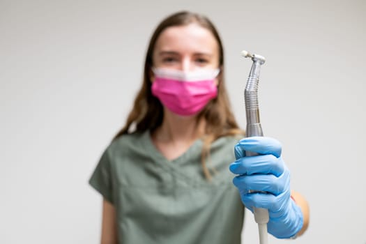 Dentiist in face mask holding dental brush.