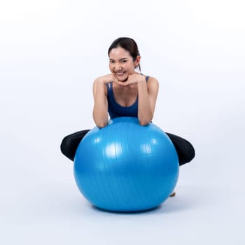 Young attractive asian woman portrait in sportswear with fit ball targeting on abs muscle for effective energetic daily workout routine. Studio shot and isolated background. Vigorous