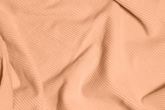 Peach fuzz, color of the year 2024, velvety fabric texture. Texture of velvet textile toned on peach fuzz color