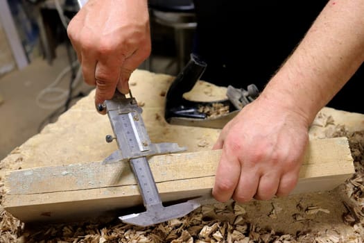 Hands with a tool on the background of a carpentry workshop. Photo in high quality.