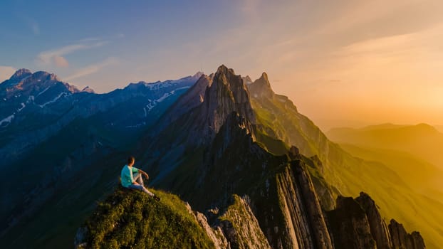 Schaeffler Mountain Ridge Swiss Alpstein Appenzell Switzerland, a mountain ridge of the majestic Schaeffler peak by Berggasthaus Schafler Switzerland. man in the mountains during sunset