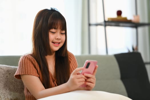 Cute preteen girl using mobile phone having fun with apps and checking social media.