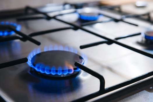 Gas kitchen stove cook with blue flames burning. Panel from steel with a gas