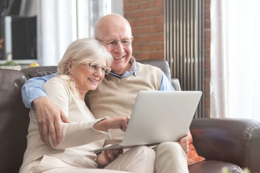 Senior couple browsing the internet together. Retirees using a laptop computer at home