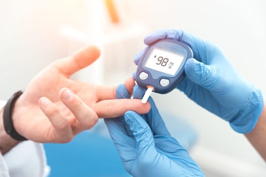 Doctor checking blood sugar level with glucometer. Treatment of diabetes concept.