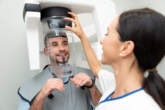 Handsome man patient standing in x-ray machine. Panoramic radiography at professional dental clinic.