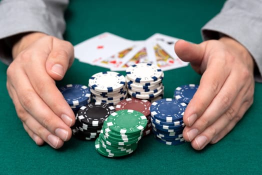 Man plays poker in the casino. Man collecting stack of poker chips, gambling concept.