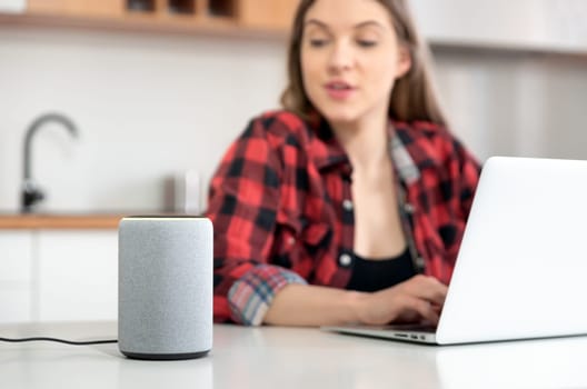 Woman talking to smart speaker. Intelligent assistant in smart home system.