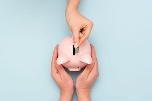Woman puts a coin in a piggy bank. Budget, money savings concept