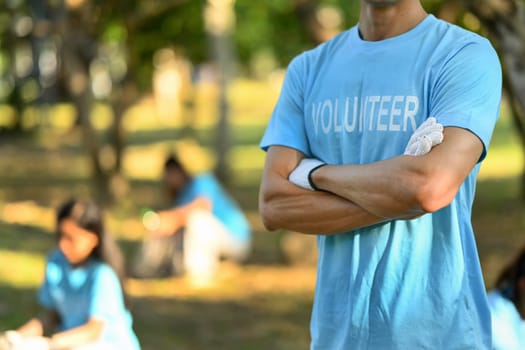 Man in volunteer uniform standing with arms crossed while standing outdoor. Charity and community service concept.