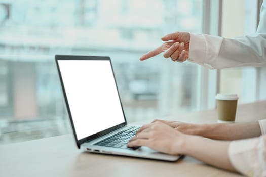 Cropped image of business colleagues using laptop computer, collaborating on project at office.