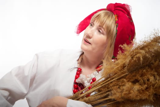 Portrait of heerful funny adult mature woman solokha with sheaf of ears. Female model in national ethnic Slavic style. Stylized Ukrainian, Belarusian or Russian woman in comic photo shoot