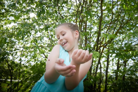 Little Happy Smiling Child Girl in blue dress on nature near greenery. SummerTime, Nature, Lifestyle and Country life