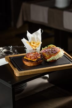 fresh tasty burger and french fries on wooden desk.