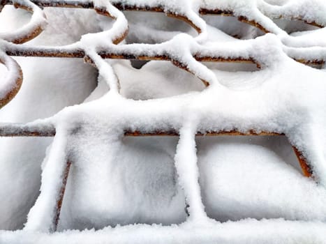 Wrought iron curly wavy lattice in the snow in winter. Abstract background, pattern, frame, texture, place for text, copy space