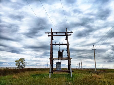Old power poles and the sky with clouds in the background. Electric lines, towers, wires in landscape