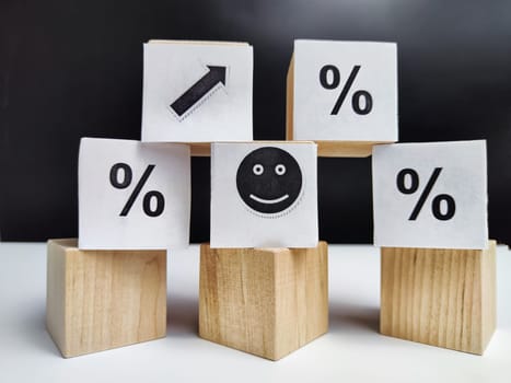 Wooden cubes in a column and row with white signs with a smiley sign, an arrow, a percentage. The concept of positivism. Positive thinking leads to the achievement of results and profits