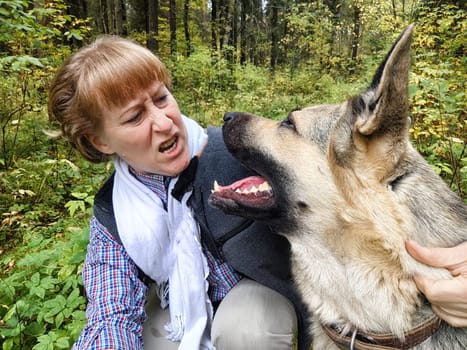 Adult girl with shepherd dog taking selfies in forest. Middle aged woman and big shepherd dog on nature. Friendship, love, communication, fun, hugs