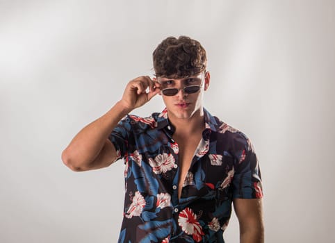 Attractive, muscular young man smiling, wearing open hawaian style shirt on white background