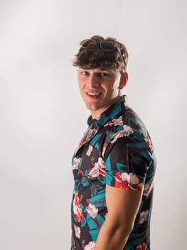 Attractive, muscular young man smiling, wearing open hawaian style shirt on white background