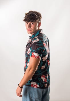 Attractive, muscular young man smiling, wearing open hawaian style shirt on white background