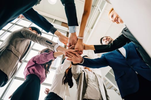 An under shot captures four diverse business colleagues in a unity circle stacking their hands. This symbolizes teamwork success and global cooperation in the corporate world.