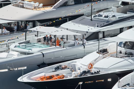 Monaco, Monte Carlo, 27 September 2022 - Invited wealthy clients inspect megayachts at the largest fair exhibition in the world yacht show MYS, port Hercules, yacht brokers, sunny weather. High quality photo