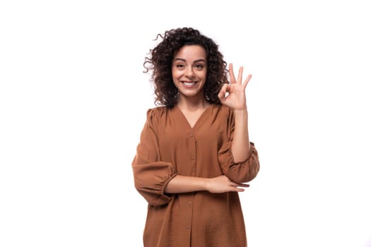 young caucasian woman with curly black hair dressed in a brown blouse.