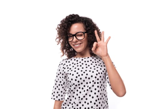 portrait of a young curly brunette well-groomed slender lady dressed in polka dot blouse in black and white.