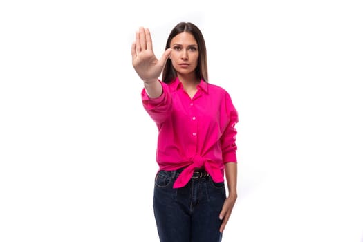 young confident caucasian brunette woman in bright pink shirt shows stop gesture.