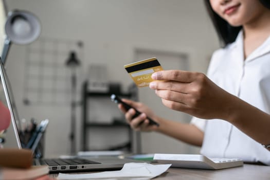 Young woman makes a purchase on the Internet on the laptop and mobile with credit card.