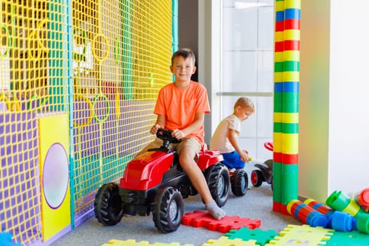 A child rides a toy pedal car at a children's play center.