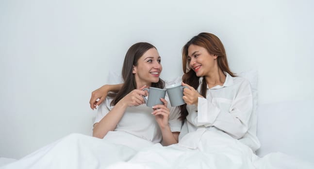 Young Asian lesbian couple sitting on bed during happy resting time Talk and relax in the bedroom..