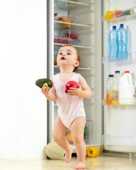 Toddler, little girl and food from fridge in kitchen for running with fresh, fruit and vegetable in hand. Youth, child and curious for organic, natural and nutrition for development of motor skill.