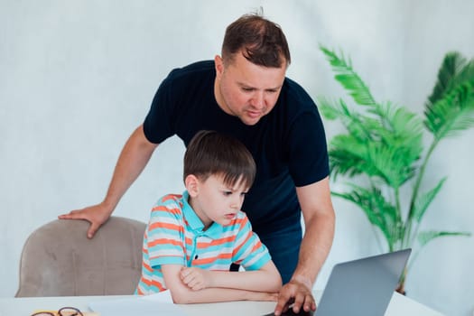 Male teacher teaches child to work on laptop