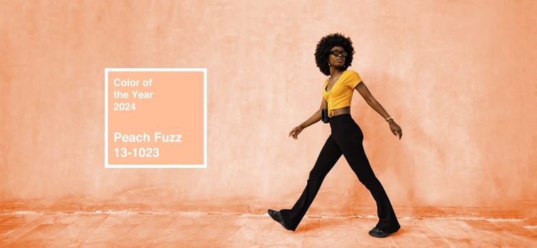 African woman model posing near the wall of Peach fuzz color of the Year 2024 concept