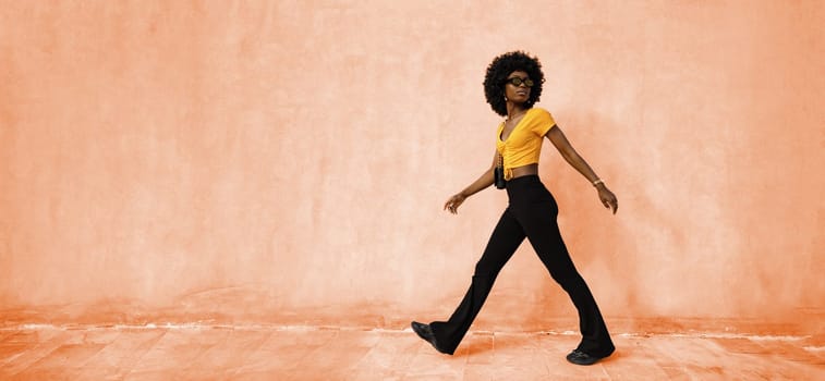 African woman model posing near the wall of Peach fuzz color of the Year 2024 concept