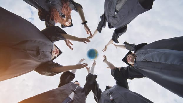 College alumni students toss a globe of the world into the sky