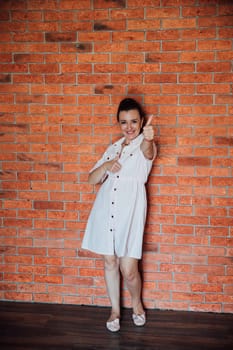 brunette woman in dress standing against brick wall