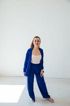 Beautiful brunette woman in blue summer suit posing in white room