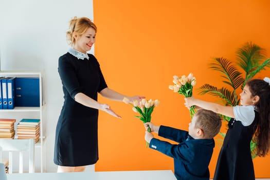 Schoolchildren giving flowers to teacher for holiday